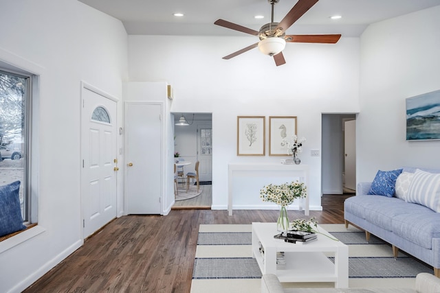 living room featuring recessed lighting, dark wood-style flooring, a towering ceiling, and baseboards