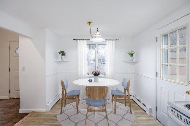 dining area featuring light wood-style floors, a baseboard radiator, and baseboard heating