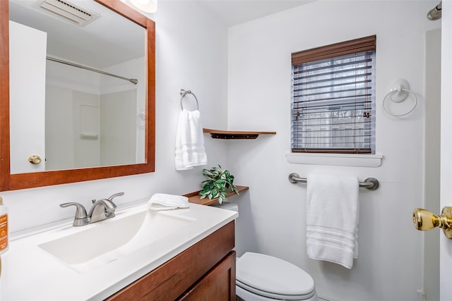 bathroom with visible vents, vanity, toilet, and walk in shower