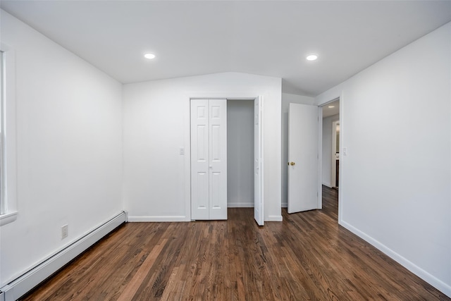 unfurnished bedroom with baseboards, a closet, a baseboard heating unit, and dark wood-type flooring