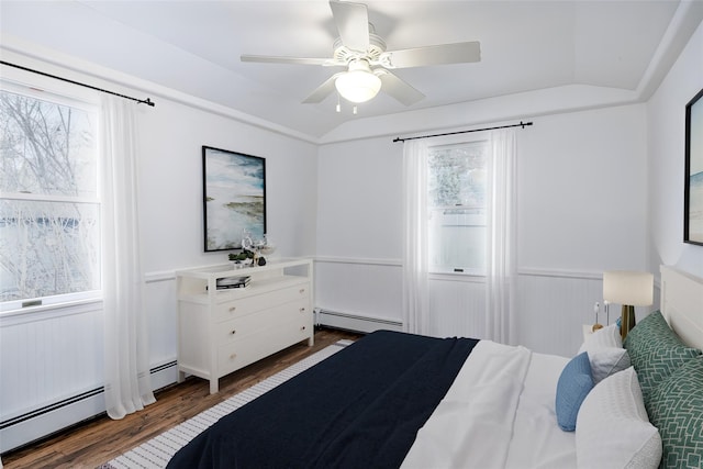 bedroom with a wainscoted wall, dark wood-type flooring, and a baseboard radiator