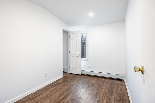 spare room with a baseboard heating unit, dark wood-style floors, and baseboards