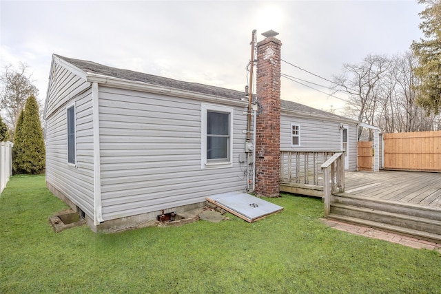 back of property with a deck, a lawn, and fence