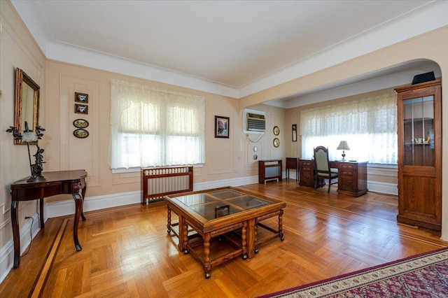 living area with a wall unit AC, radiator heating unit, and baseboards