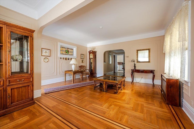 interior space featuring arched walkways, baseboards, and a decorative wall