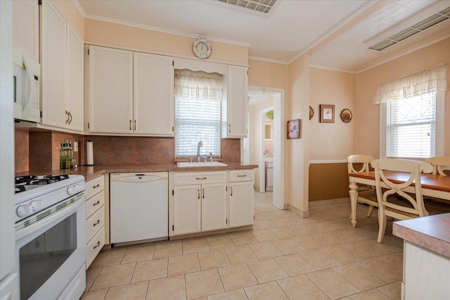 kitchen featuring white appliances, plenty of natural light, white cabinetry, and a sink