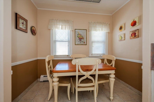 dining room with baseboards, light tile patterned flooring, a baseboard radiator, and crown molding