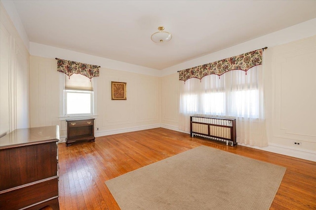 interior space with a decorative wall, wood finished floors, and radiator