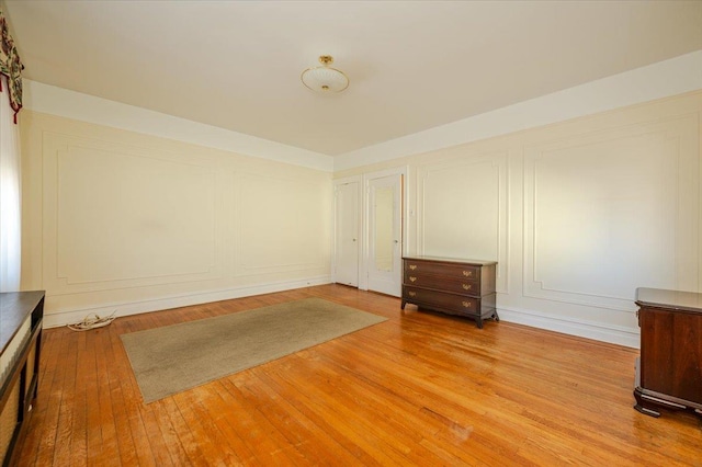 spare room with a decorative wall and wood finished floors