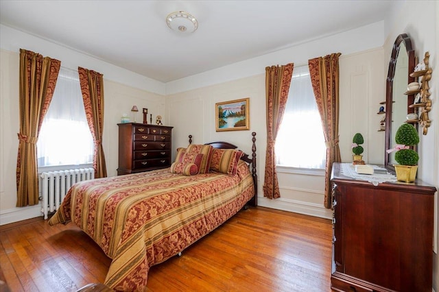 bedroom featuring baseboards, radiator heating unit, and wood finished floors