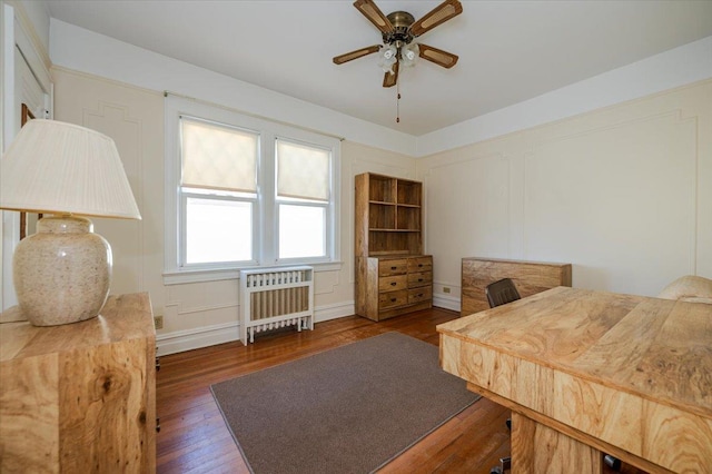 bedroom with a decorative wall, dark wood-style flooring, baseboard heating, and radiator