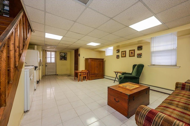 living area featuring light tile patterned floors, a baseboard heating unit, and a drop ceiling