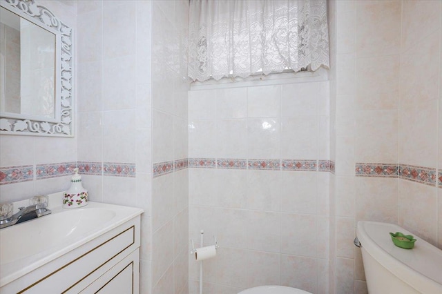 half bath featuring toilet, tile walls, and vanity