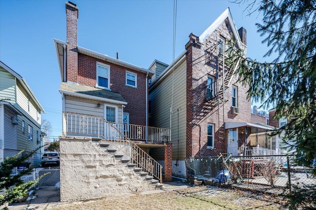 exterior space featuring brick siding, stairway, a chimney, and fence