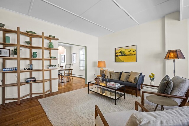 living area featuring a baseboard heating unit, a paneled ceiling, and wood finished floors