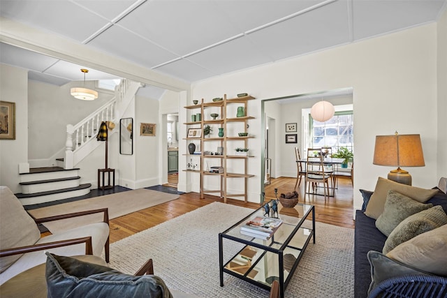 living area featuring stairs, wood finished floors, and baseboards