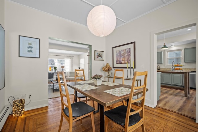 dining space featuring baseboards, baseboard heating, and wood finished floors