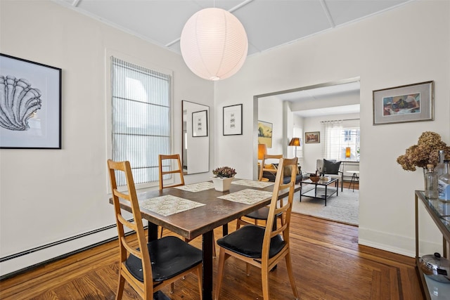 dining area with a baseboard heating unit, dark wood-type flooring, and baseboards