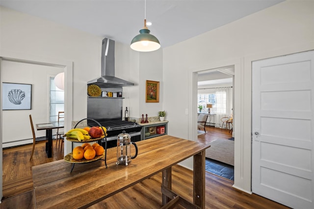 kitchen featuring wall chimney range hood, a baseboard radiator, dark wood finished floors, and gas range