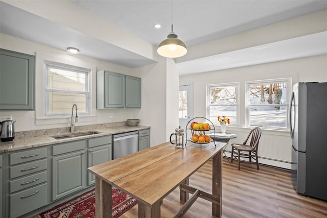 kitchen featuring appliances with stainless steel finishes, a baseboard heating unit, a healthy amount of sunlight, and a sink