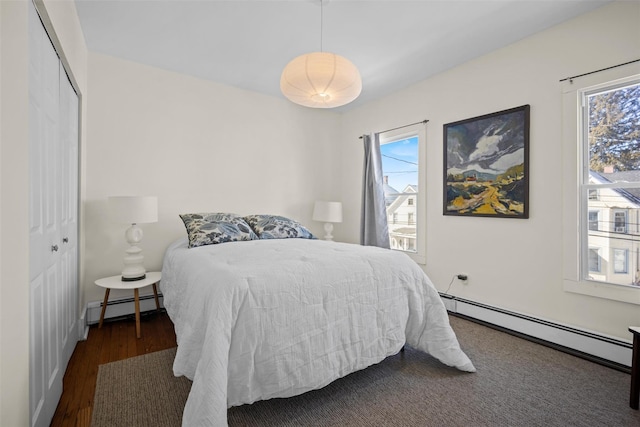 bedroom featuring a baseboard radiator, a closet, and dark wood-style flooring