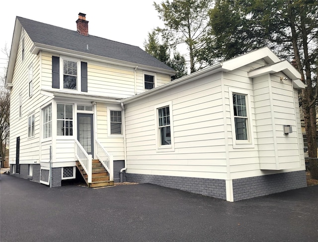 back of house with entry steps and a chimney