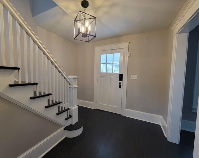 entrance foyer featuring dark wood-style floors, a chandelier, stairs, and baseboards