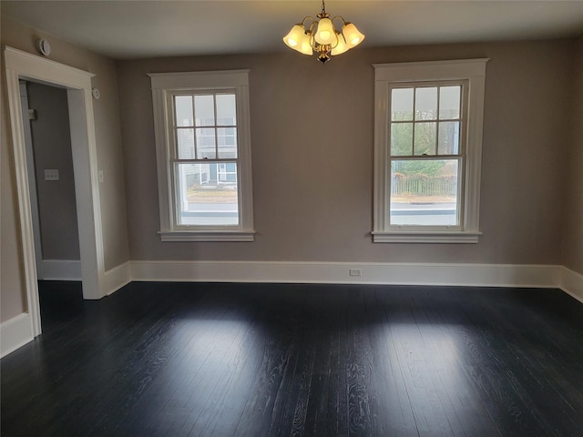 unfurnished dining area with a chandelier, dark wood finished floors, and baseboards