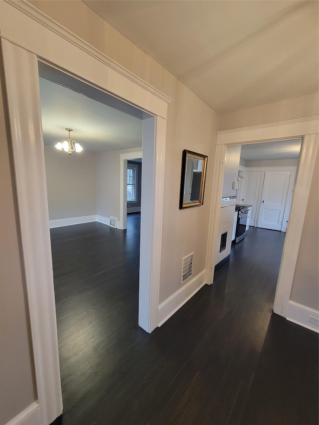 corridor featuring dark wood-type flooring, visible vents, and baseboards