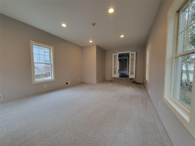 spare room featuring recessed lighting, light carpet, and visible vents