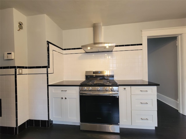 kitchen with gas stove, white cabinets, dark countertops, and wall chimney exhaust hood