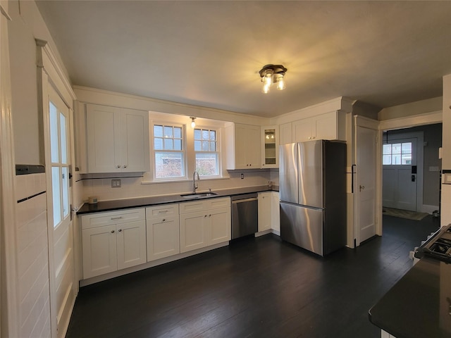 kitchen with dark countertops, dark wood finished floors, stainless steel appliances, and a sink