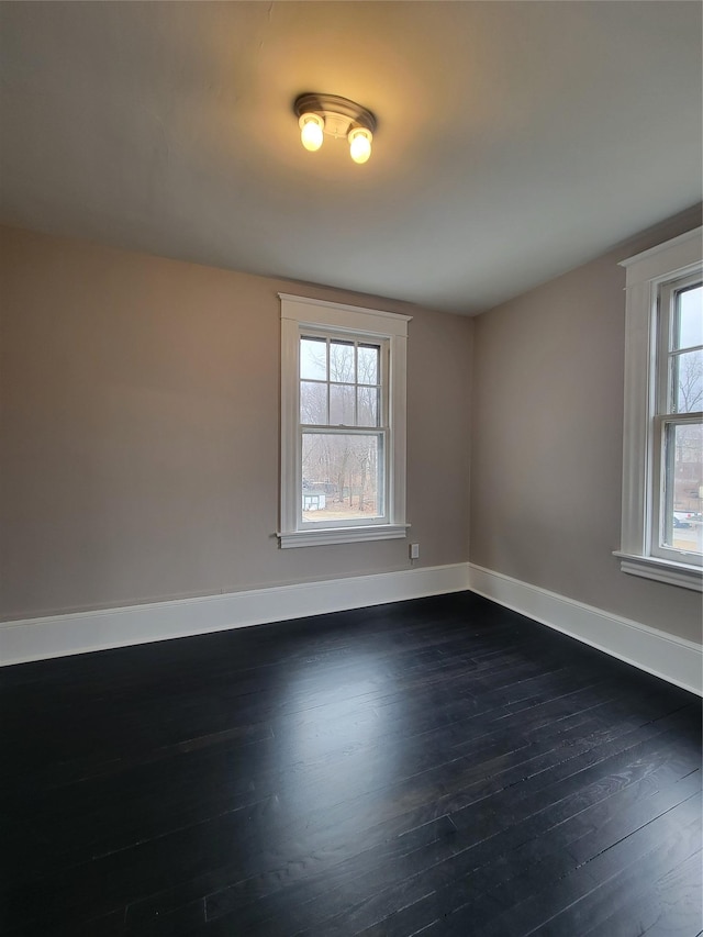 empty room with dark wood-style flooring and baseboards