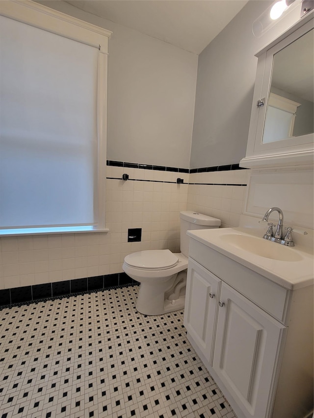 bathroom featuring tile walls, a wainscoted wall, vanity, and toilet