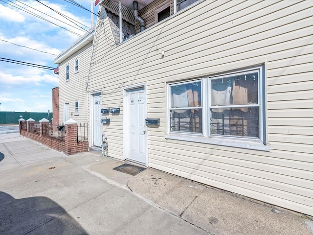 view of exterior entry with a patio and fence