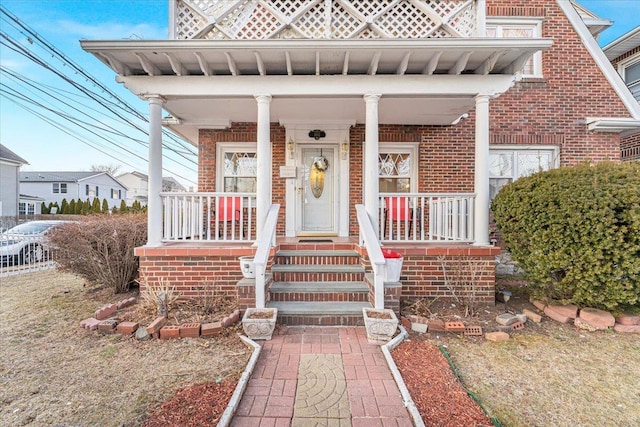 property entrance featuring brick siding and a porch