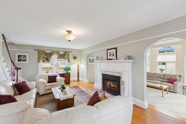 living room with wood finished floors, stairway, a fireplace with flush hearth, and baseboards