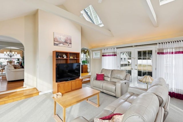 living area featuring arched walkways, high vaulted ceiling, a chandelier, carpet floors, and french doors