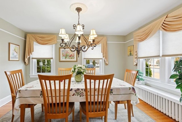 dining area with baseboards, a notable chandelier, wood finished floors, and radiator