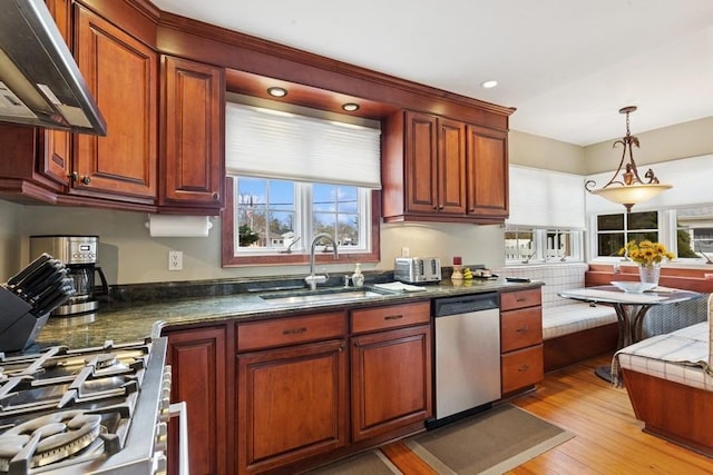 kitchen with dark countertops, decorative light fixtures, extractor fan, stainless steel appliances, and a sink