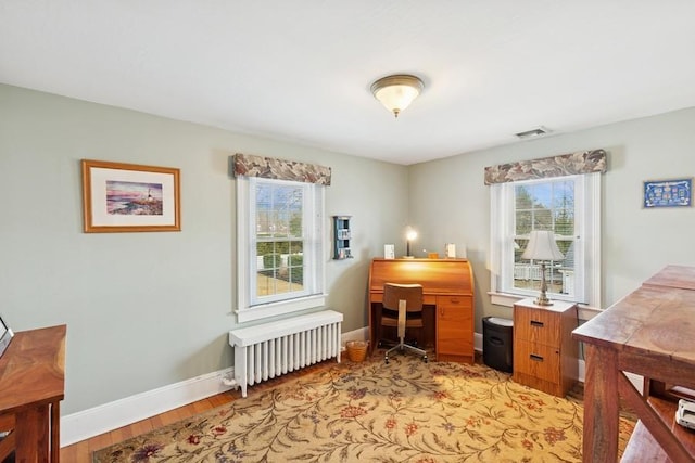 office area with radiator, plenty of natural light, and baseboards