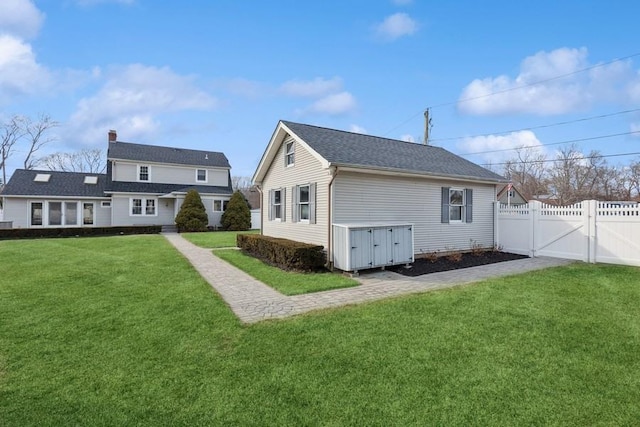 back of property with a gate, a lawn, and fence