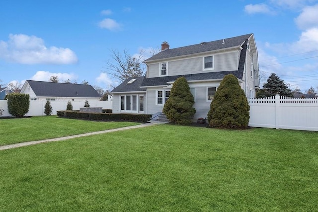 back of house featuring a yard, entry steps, fence, and a chimney