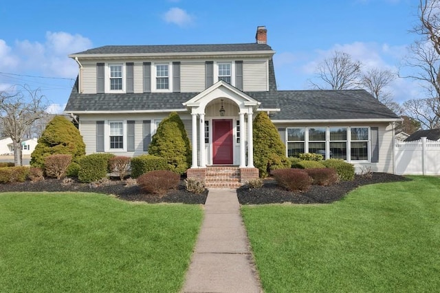 view of front of home with entry steps, fence, roof with shingles, a front lawn, and a chimney