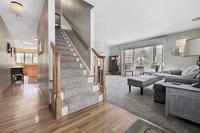 living area with stairs, visible vents, and wood finished floors