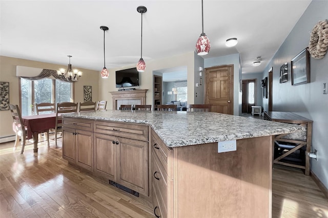 kitchen featuring light wood-style flooring, a kitchen island, light stone counters, and open floor plan