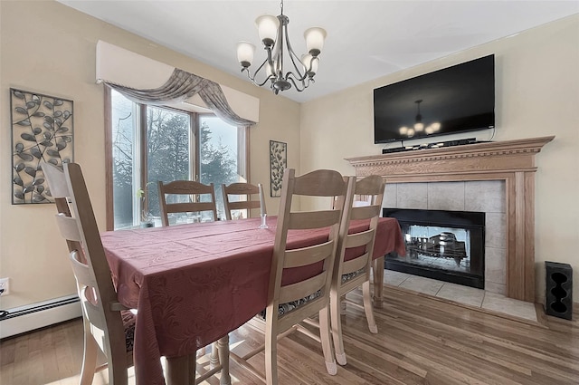 dining room with a baseboard heating unit, a notable chandelier, a fireplace, and wood finished floors