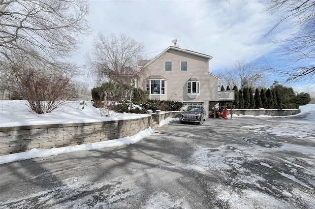 view of snow covered exterior with aphalt driveway and a chimney