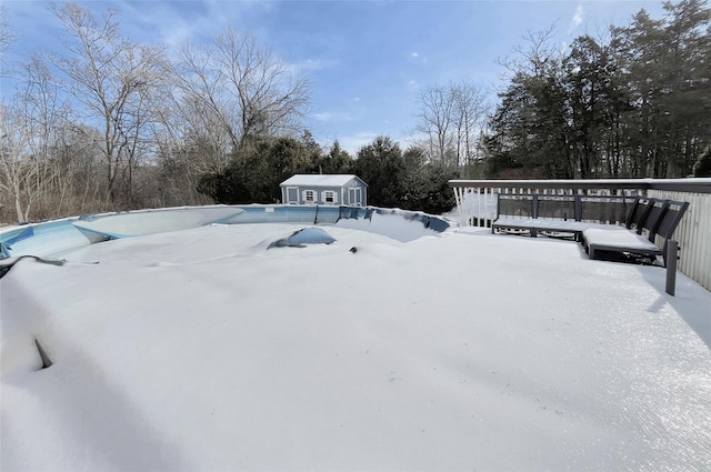 yard covered in snow featuring a covered pool, a shed, and an outbuilding