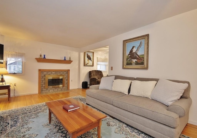 living area featuring a fireplace, plenty of natural light, wood finished floors, and baseboards